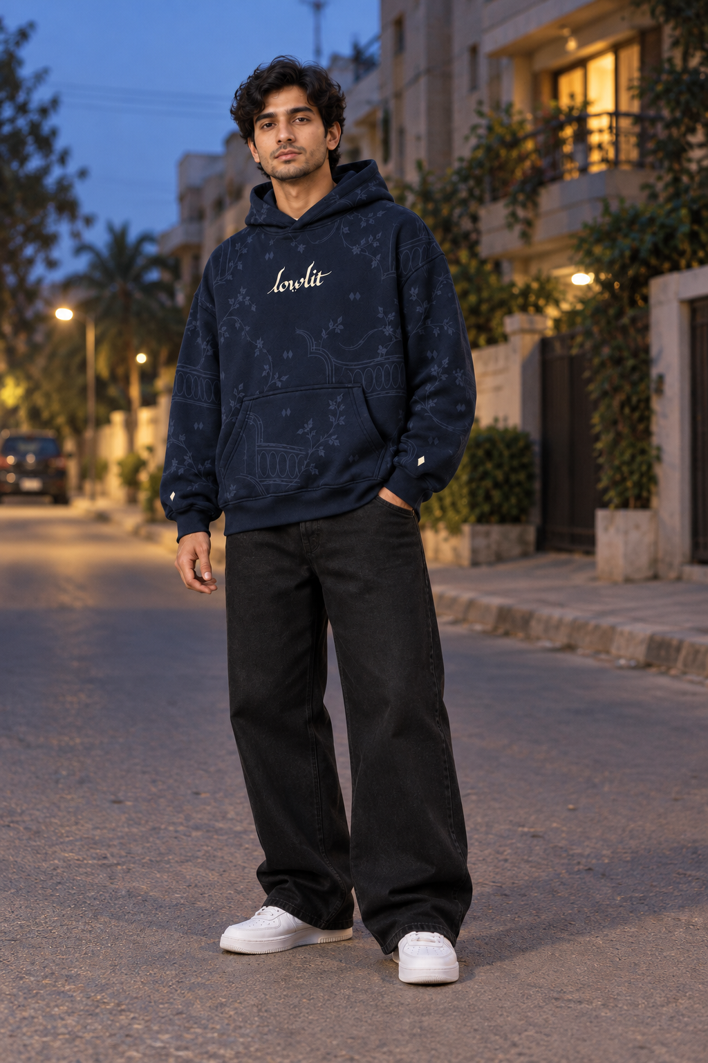 LOWLIT navy hoodie styled with baggy black jeans on a quiet street at dusk